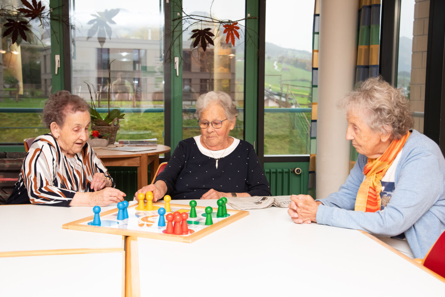 Drei Bewohnerinnen sitzen am Tisch und spielen gemeinsam das Spiel Eile mit Weile.